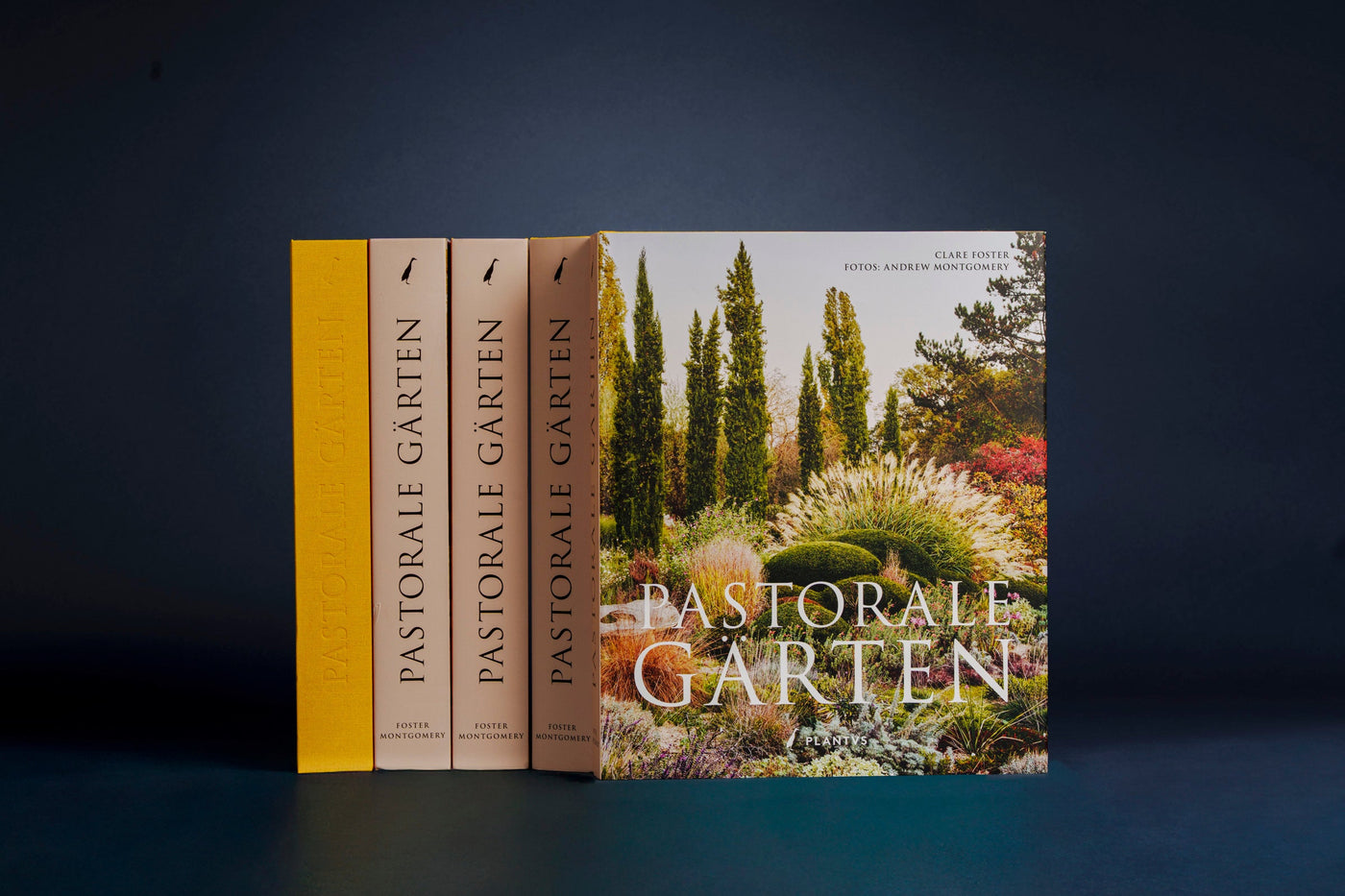 Bildband Pastorale Gärten – vier Bände mit gelbem Leineneinband und Cover mit Zypressen-Gartenmotiv vor dunkelblauem Hintergrund